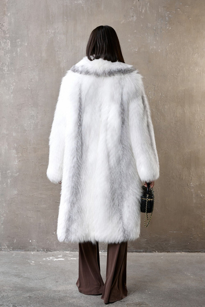 Woman draped in a rich and voluminous fox fur coat, exuding refined glamour with its natural gray and white hues and sumptuous finish.