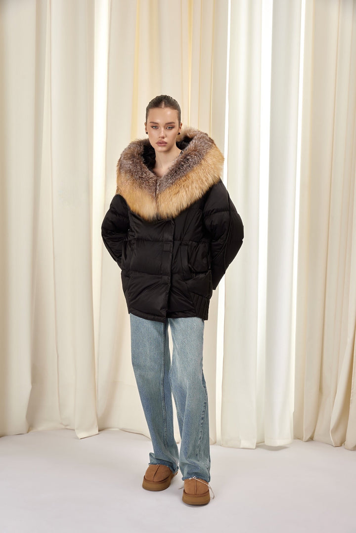 A woman models a black insulated down jacket with a soft fox fur-lined hood, blending cozy comfort with chic winter style.