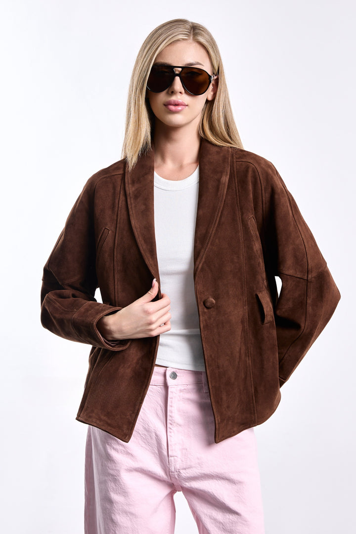 A woman dressed in a chic brown suede jacket with a belted waist and tailored cut, combining relaxed fit with structured elegance for a versatile, polished look.