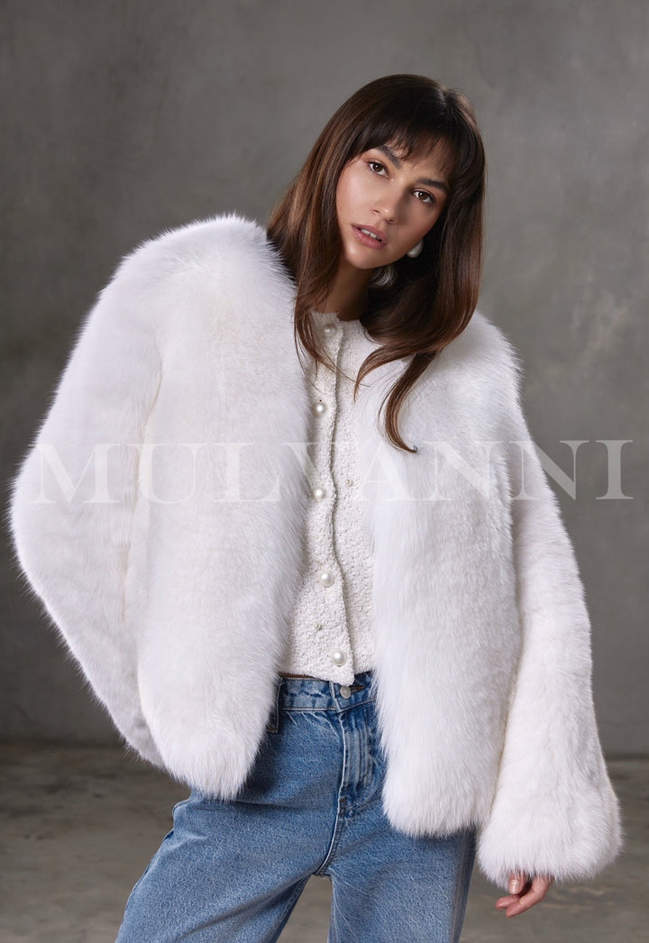 Woman wears a cropped Arctic fox fur coat with full pelt design, radiating luxury and warmth in a bold yet sophisticated winter look.