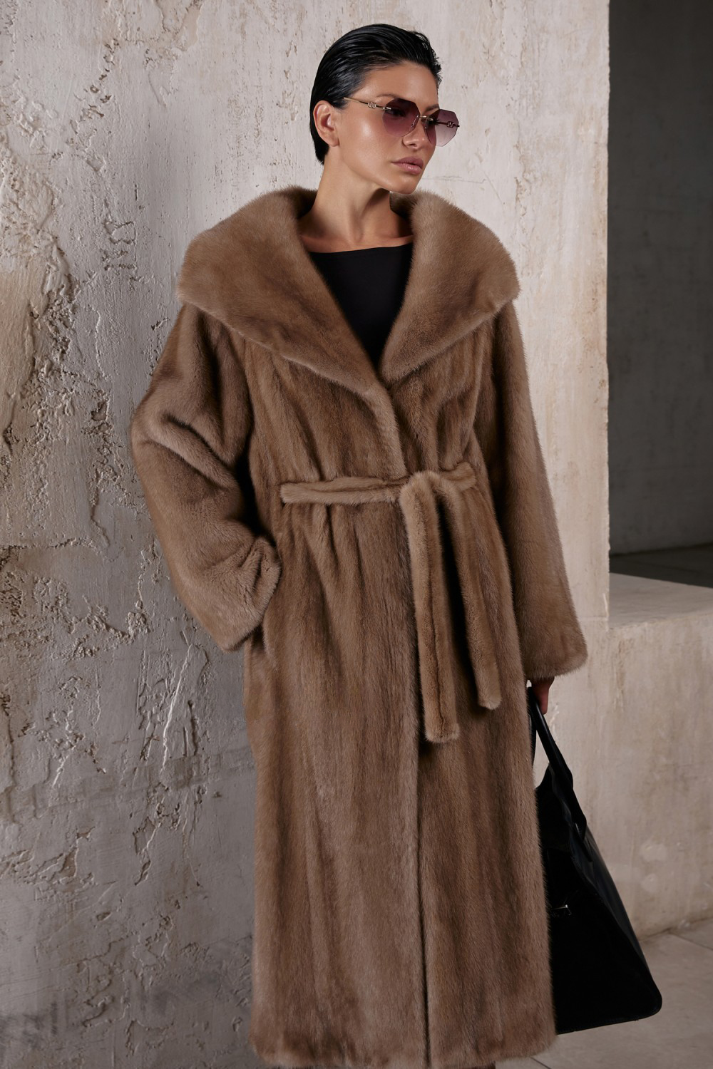 Light brown long mink fur coat with hood and waist belt, exuding luxury and elegance in a stylish setting.