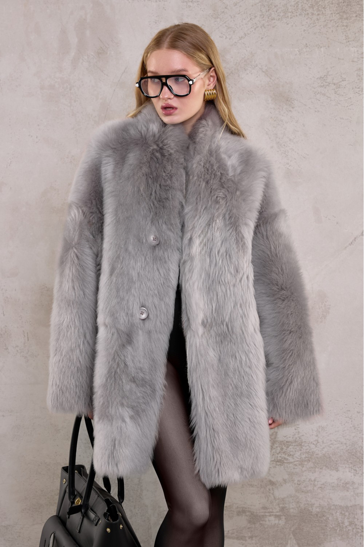 Luxurious genuine shearling coat in light grey, styled for refined cold-weather fashion.
