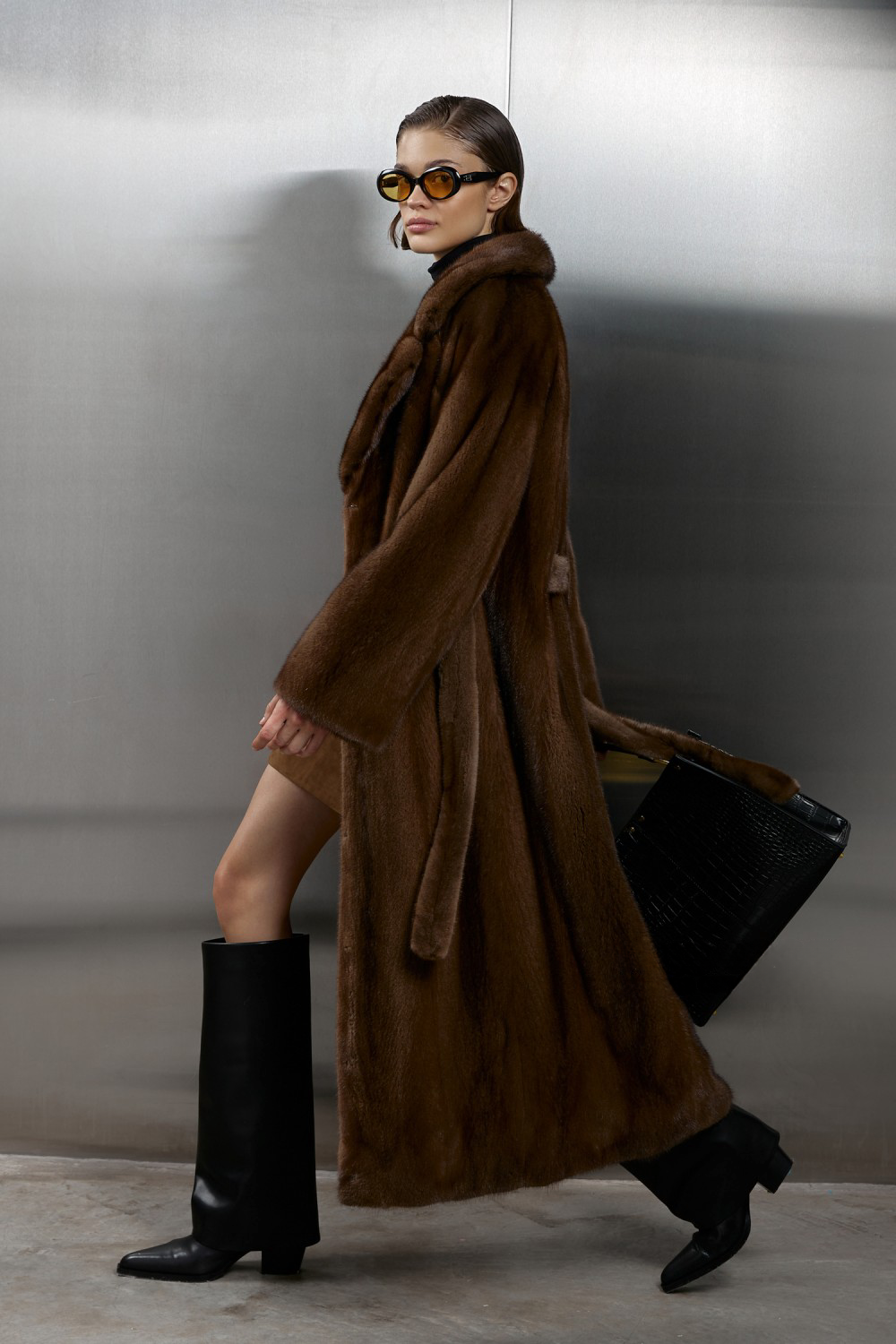 Model showcasing a luxurious long genuine brown mink fur coat, exuding elegance and style against a sleek backdrop.