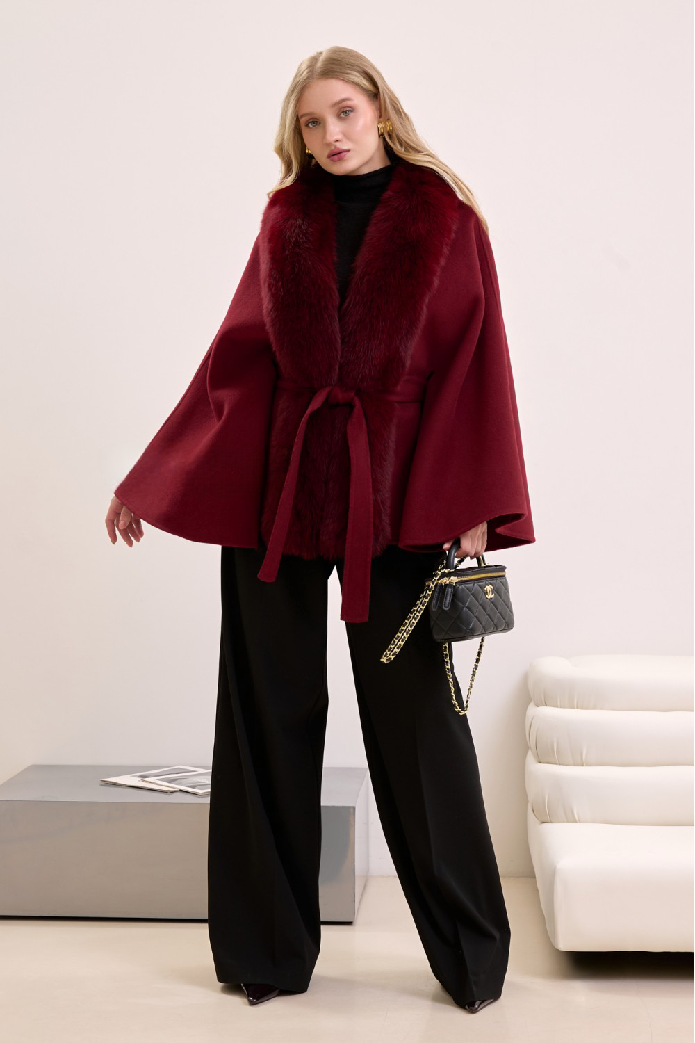 Elegant woman in burgundy cashmere cape with fox fur trim, showcasing rich color and luxurious winter style.