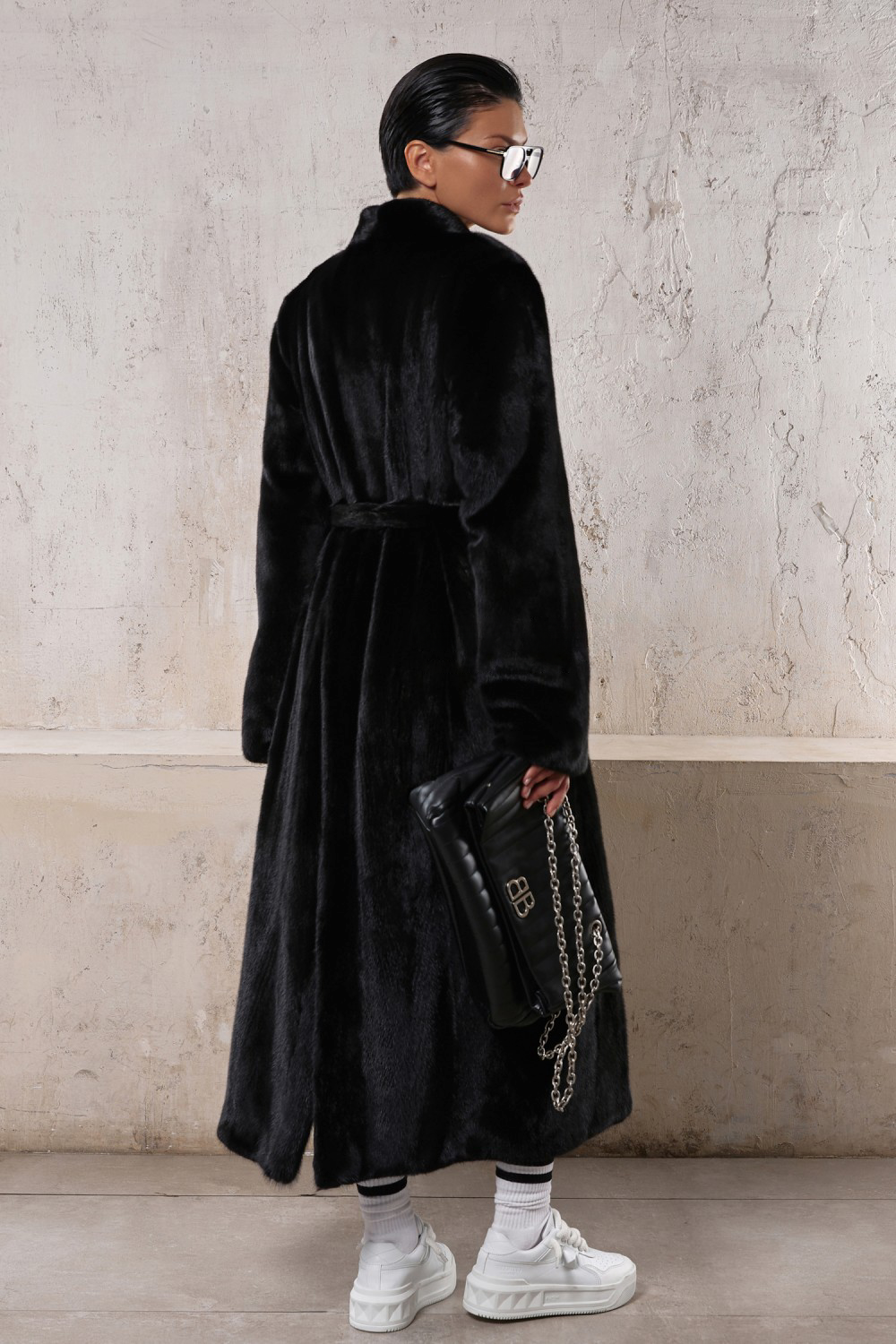 Stylish model in a long black mink coat, perfect for both formal and sporty looks.