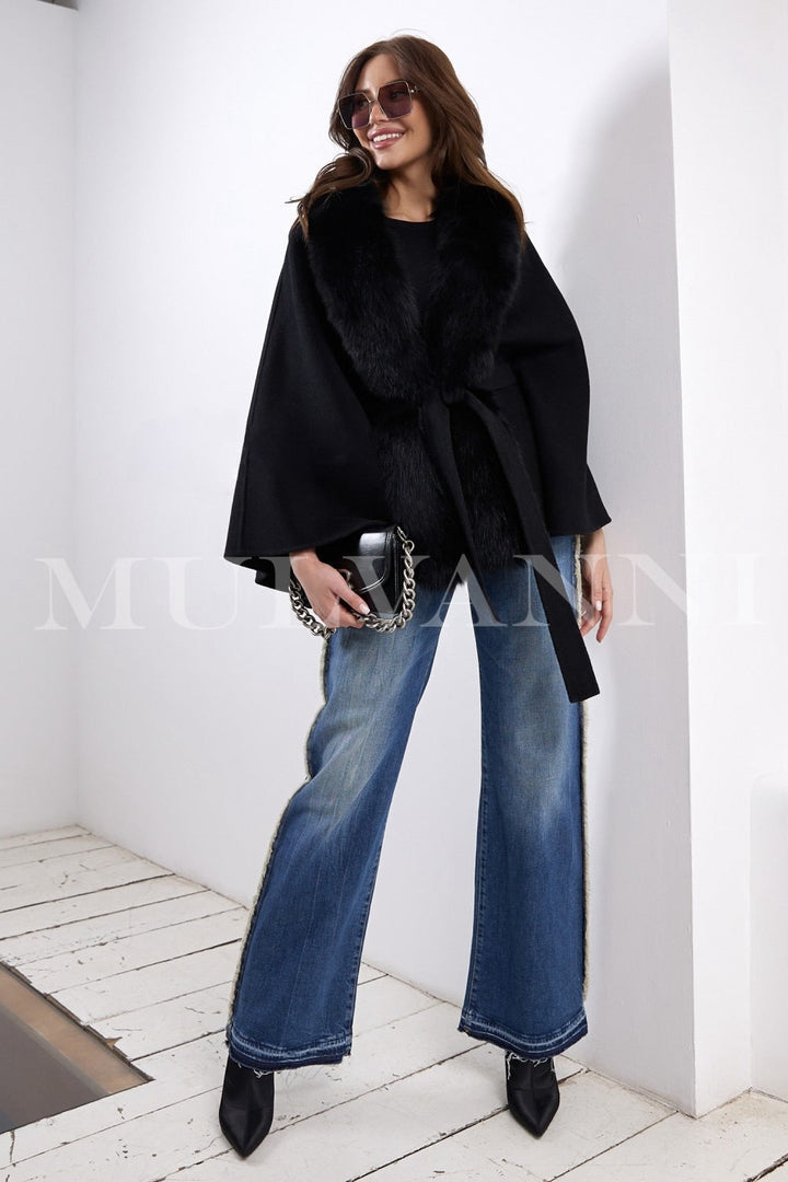 A woman models a luxurious black cashmere cape featuring genuine fox fur accents, combining warmth and refined style that can be worn effortlessly in any season.