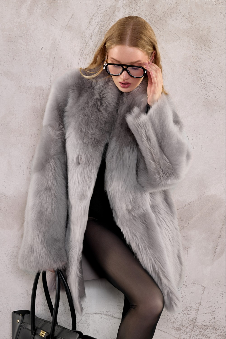 Woman wearing sunglasses, leather bag and a light grey shearling coat. Warm, elegant, and effortlessly chic.