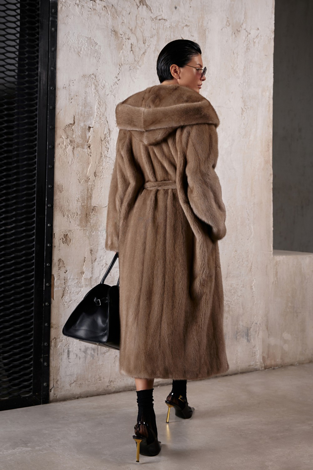 Light brown long mink fur coat with hood and waist belt, showcasing elegant design and luxurious warmth.
