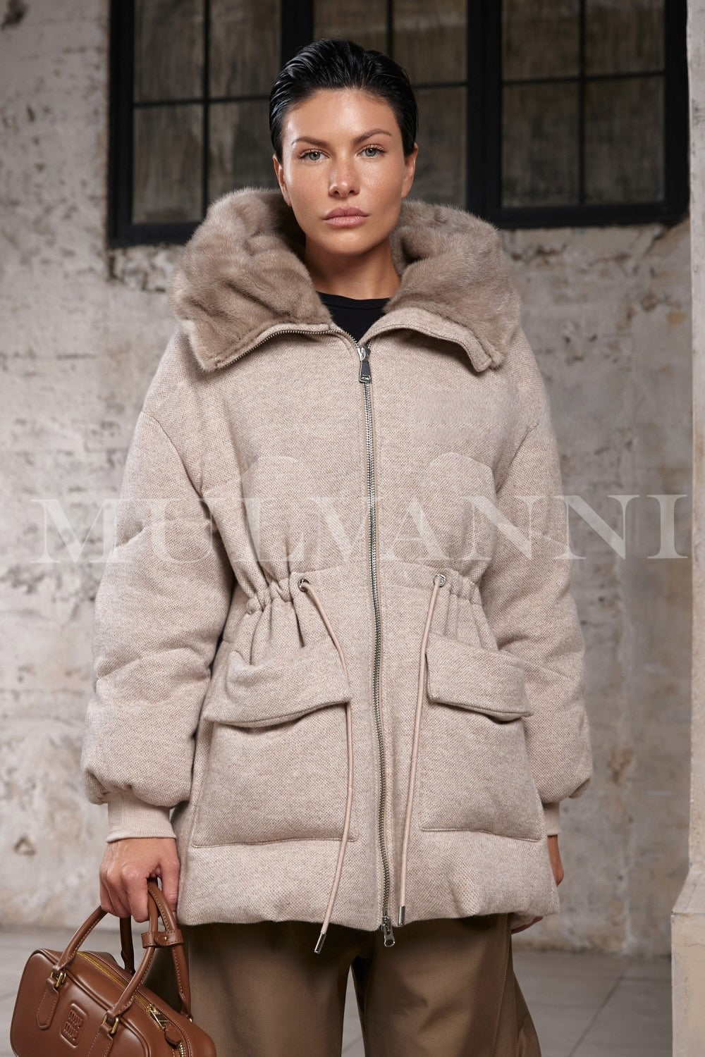 A woman wears a luxurious double-face down jacket with a voluminous mink fur hood, styled elegantly for cold weather.