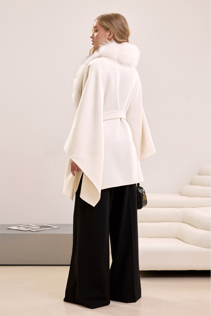 Woman in flowing cashmere and fox fur cape, blending warmth, elegance, and classic winter fashion.