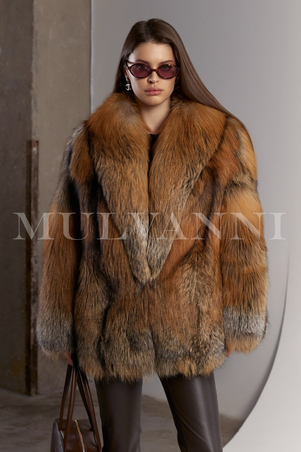 Woman wears a voluminous red fox fur coat paired with brown leggings and a matching brown leather handbag, showcasing a warm and luxurious winter look.