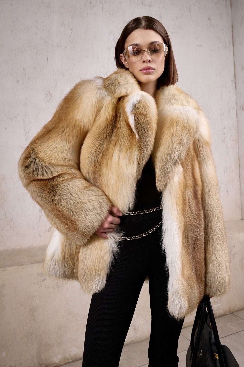 A woman wearing a full pelt gold fox fur coat and sunglasses, radiating luxury and confidence in this high-quality winter piece designed for Arctic-level warmth.