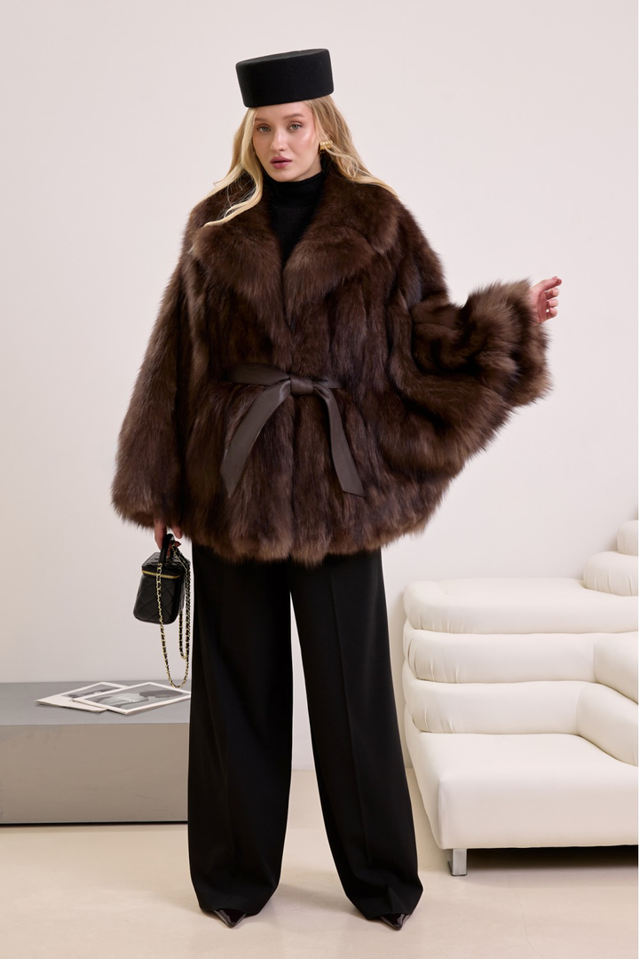 Model in a voluminous fox fur coat featuring a cinched waist and classic silhouette, perfect for cold-weather elegance.
