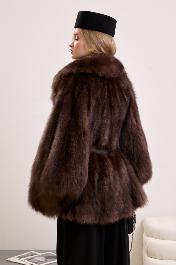 Statement winter coat made of plush natural fox fur, styled with a sleek leather belt for added shape and style.