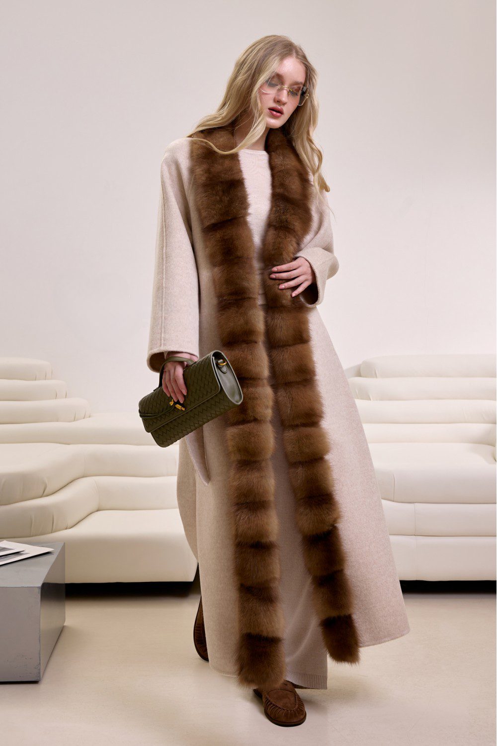 Chic and sophisticated cashmere coat with mink fur, belted and worn by a stylish woman indoors. 