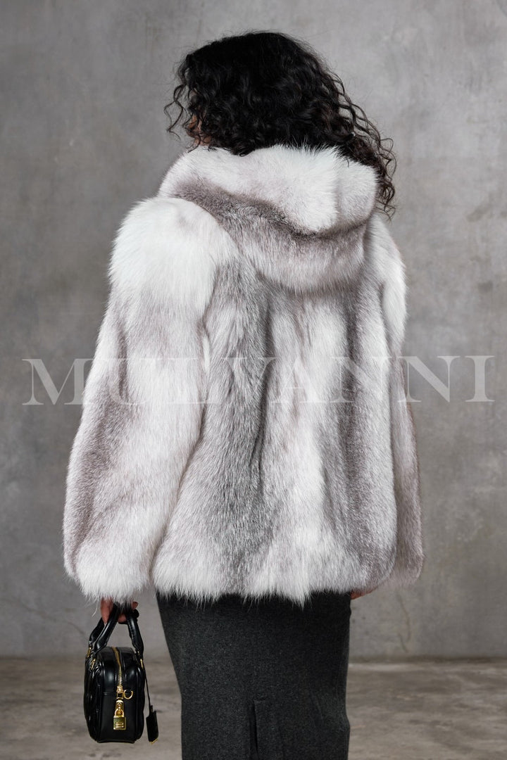 This Arctic fox fur coat, worn by a woman, showcases unmatched softness and a loose, elegant fit with a cozy hood, providing exceptional warmth suitable for temperatures as low as -25ºC.