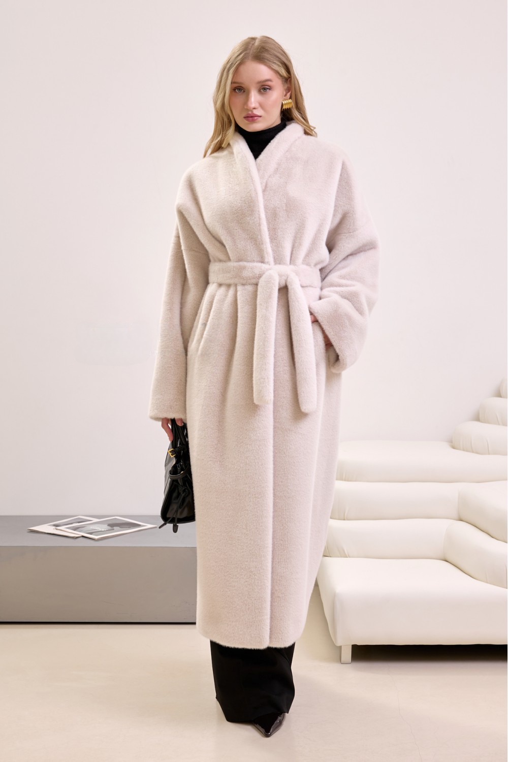 Elegant woman in long beige faux fur coat with belt, showcasing soft texture and refined winter style.