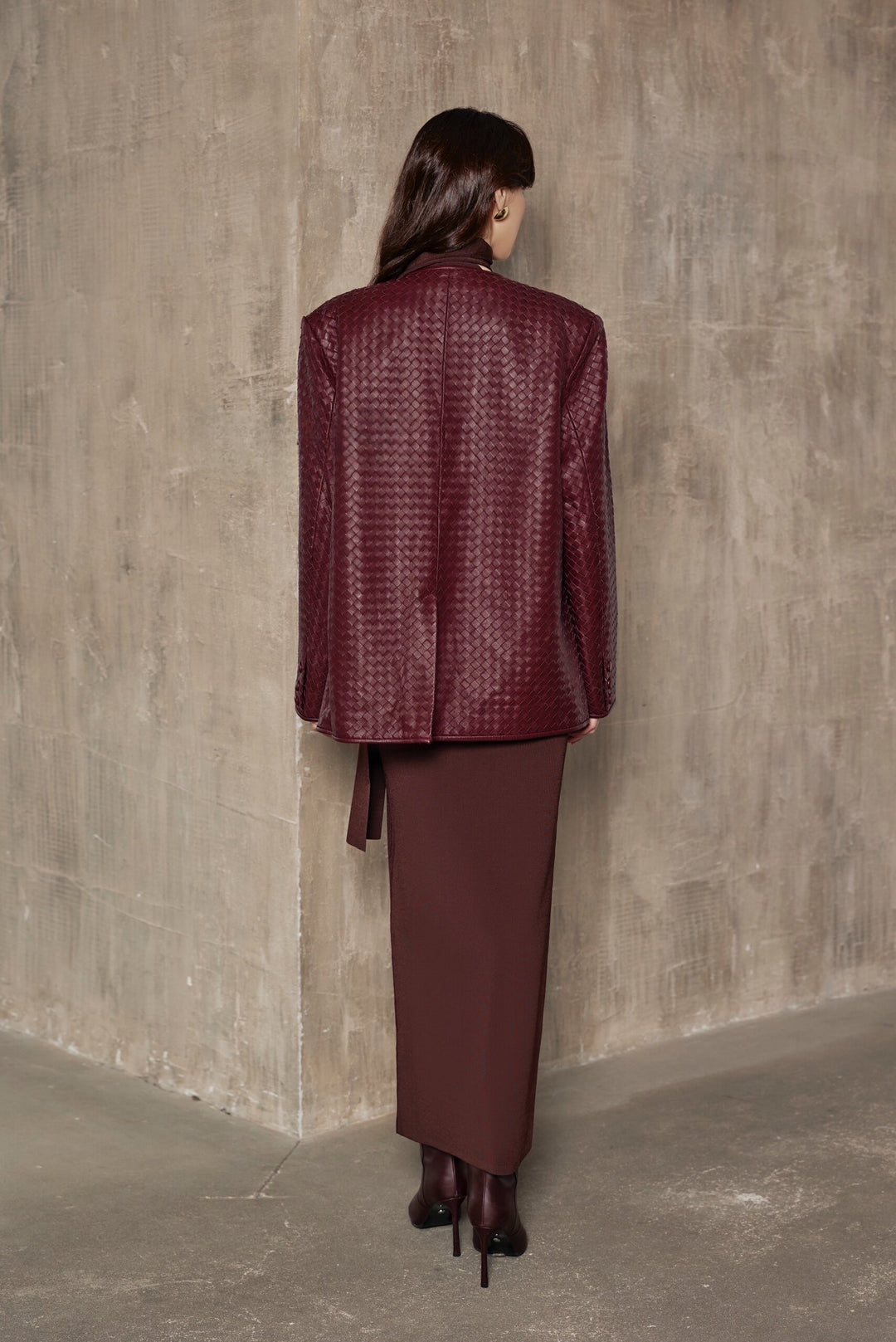 A woman models a burgundy woven blazer with a sleek, tailored fit and strong shoulders, embodying effortless elegance and modern chic.