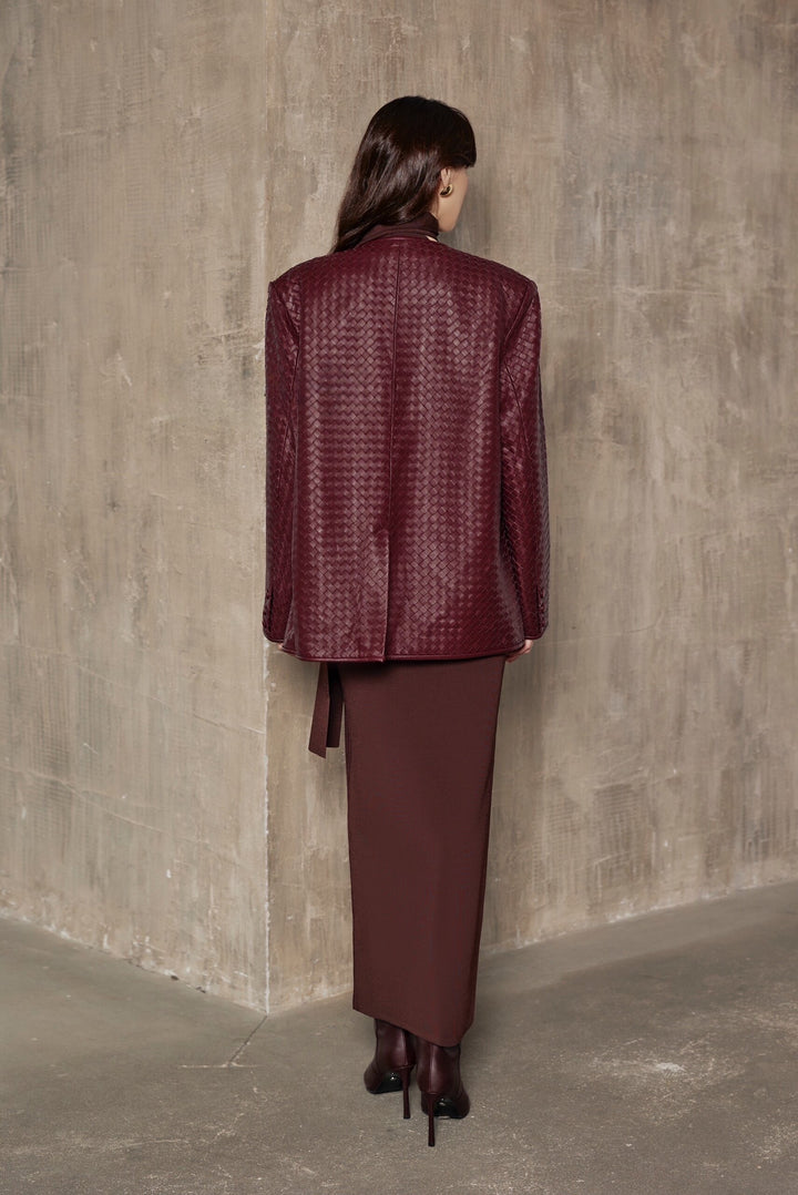 A woman models a burgundy woven blazer with a sleek, tailored fit and strong shoulders, embodying effortless elegance and modern chic.