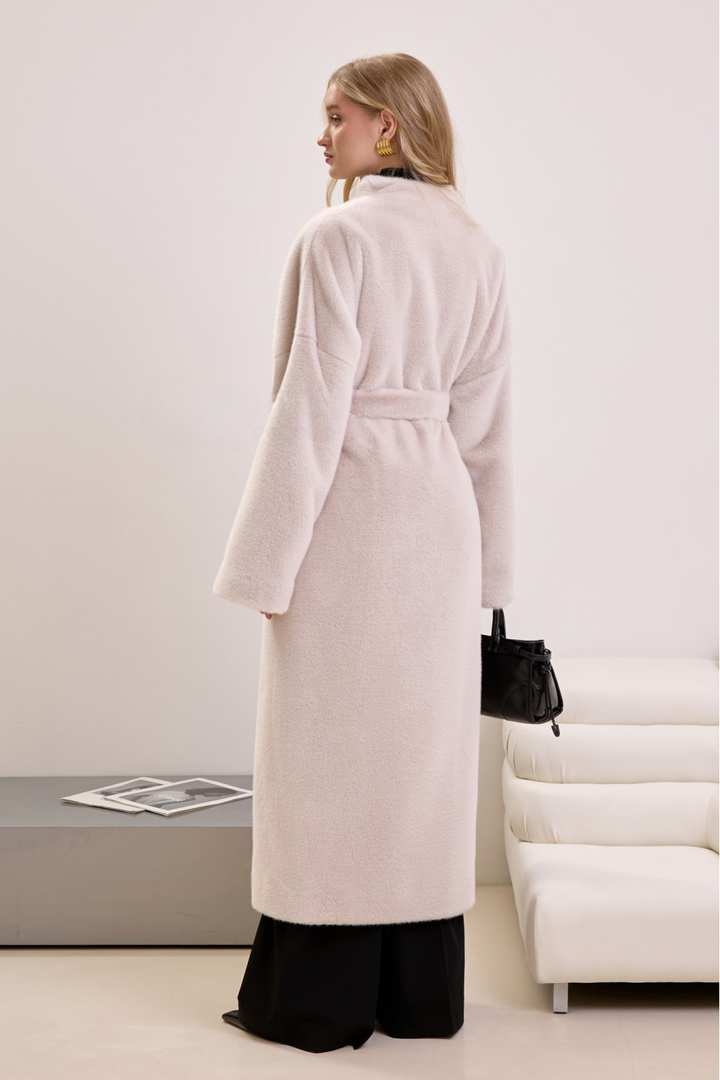 Woman wearing beige faux fur outerwear with a belted silhouette, blending comfort with minimalist luxury.
