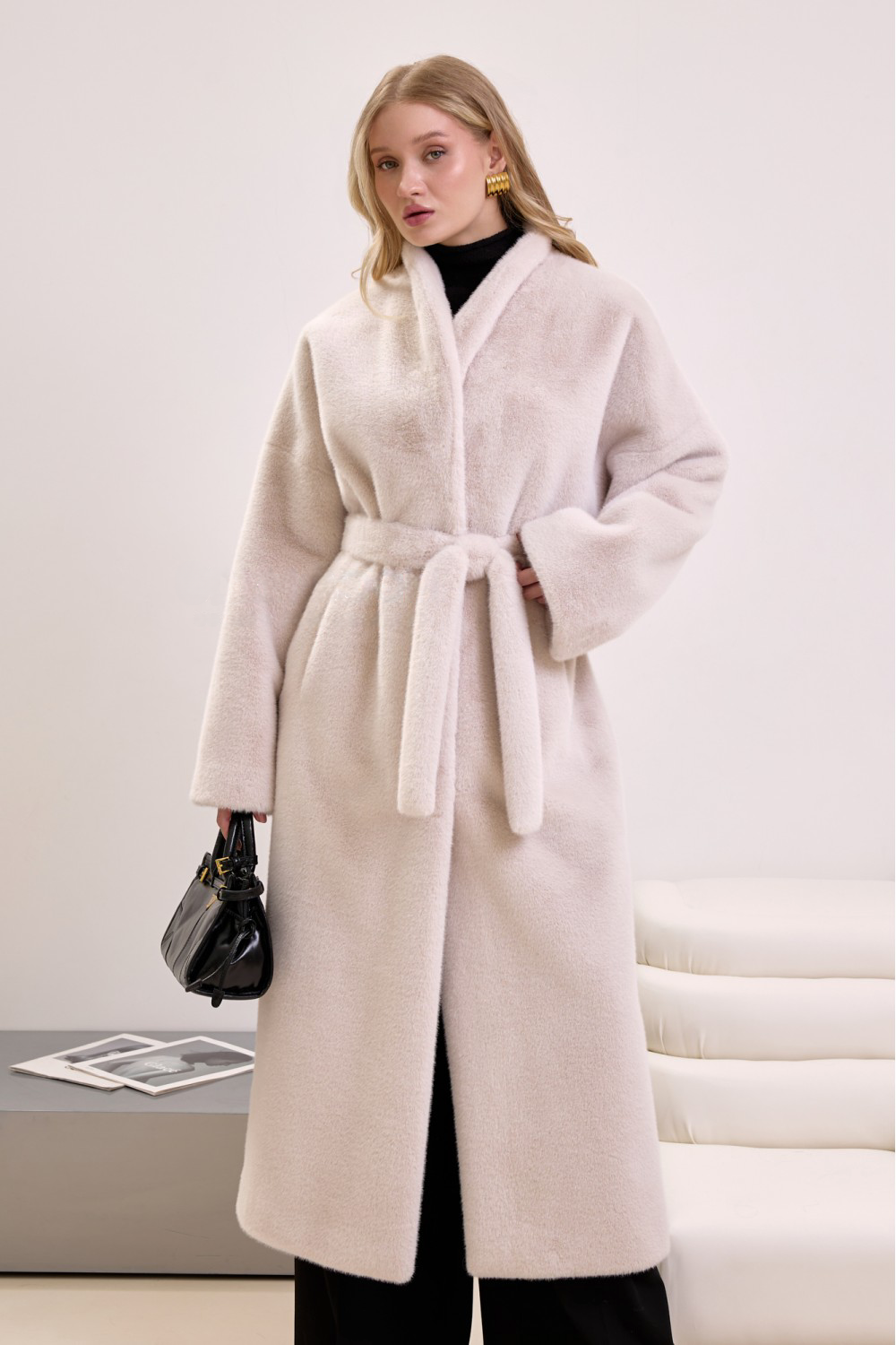 Chic belted faux fur coat in beige, worn by woman for a luxurious and cozy cold-weather look.