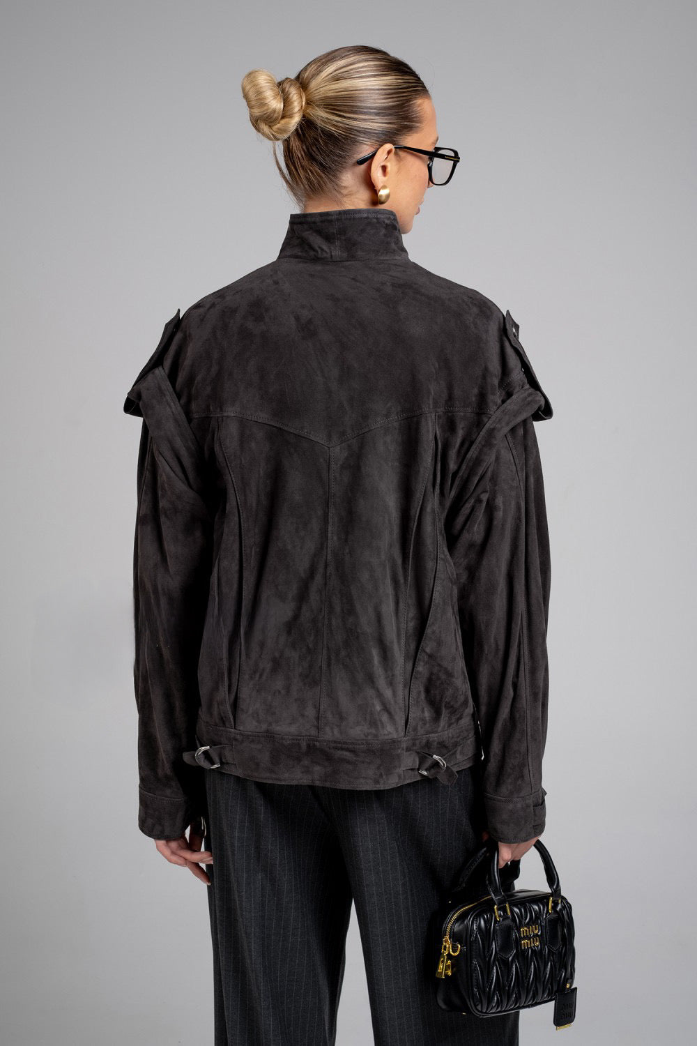 A woman is seen wearing a charcoal suede jacket with a sleek silhouette and rich color, perfect for casual or elevated looks.