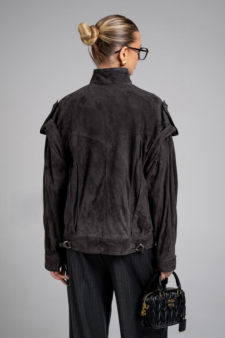 A woman is seen wearing a charcoal suede jacket with a sleek silhouette and rich color, perfect for casual or elevated looks.