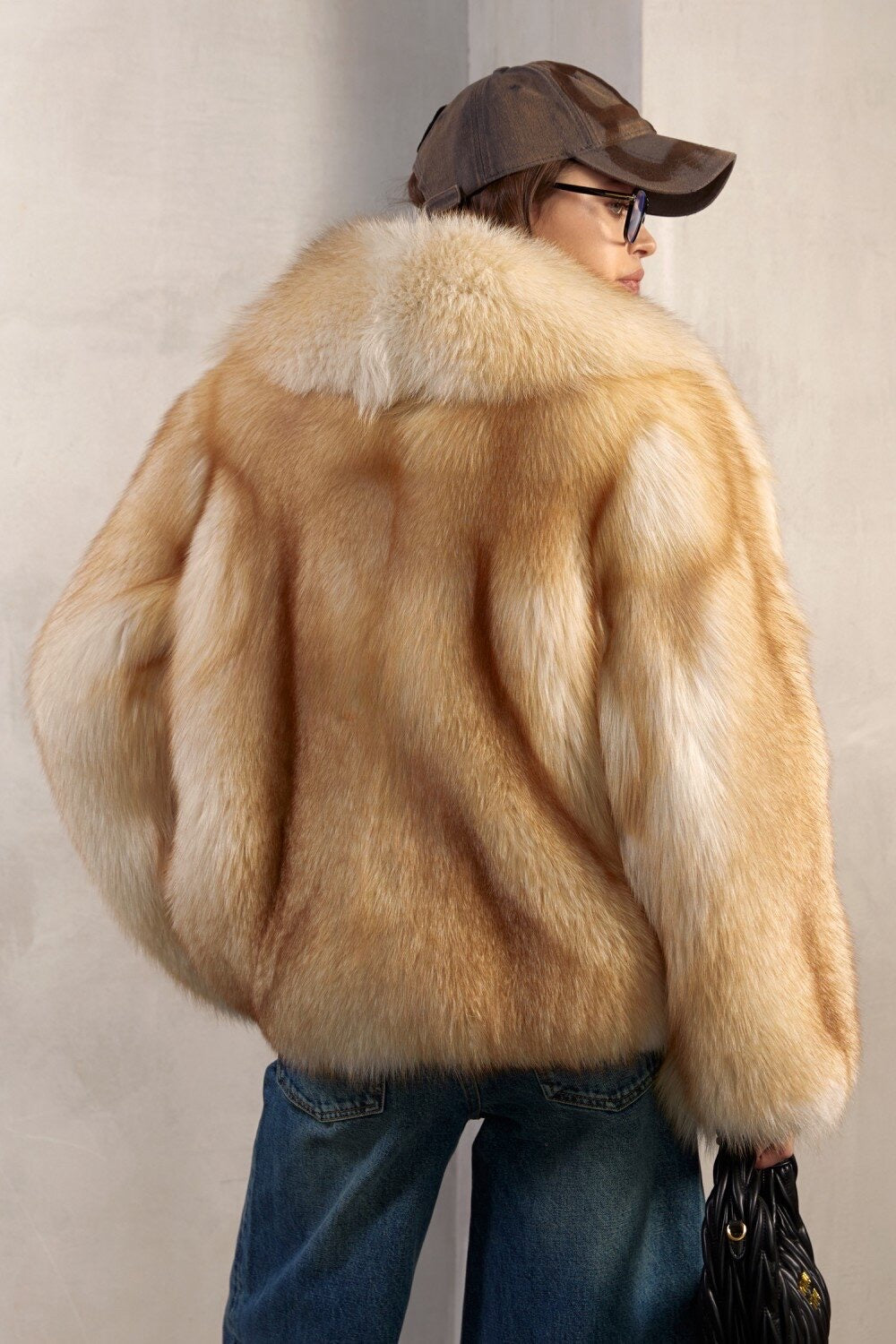 A woman dressed in a striking full pelt gold fox fur coat, exuding luxury, comfort, and sophistication in every detail.