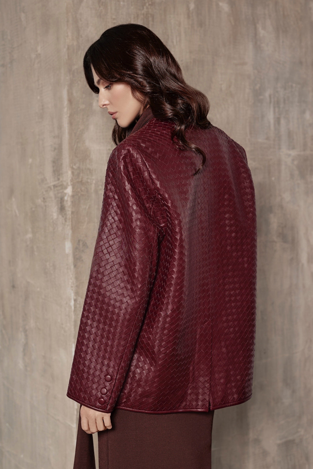A woman wearing a sharp-shouldered burgundy blazer that combines bold structure with sophisticated design for a polished, fashionable look.