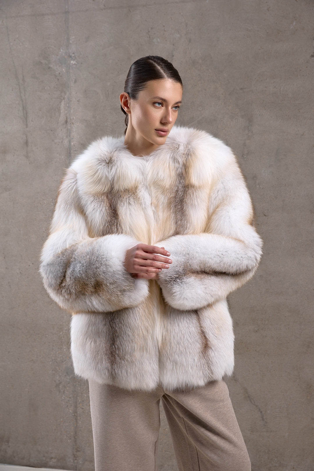 A woman exudes sophistication in a full-bodied fox fur coat featuring golden cross tones, designed for elegance and resilience against harsh climates.