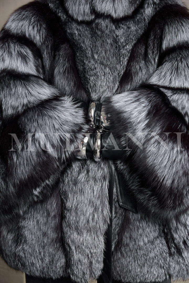 A graceful woman walks in a stunning silver fox fur coat with flowing fur and a defined waist, radiating upscale winter glamour.