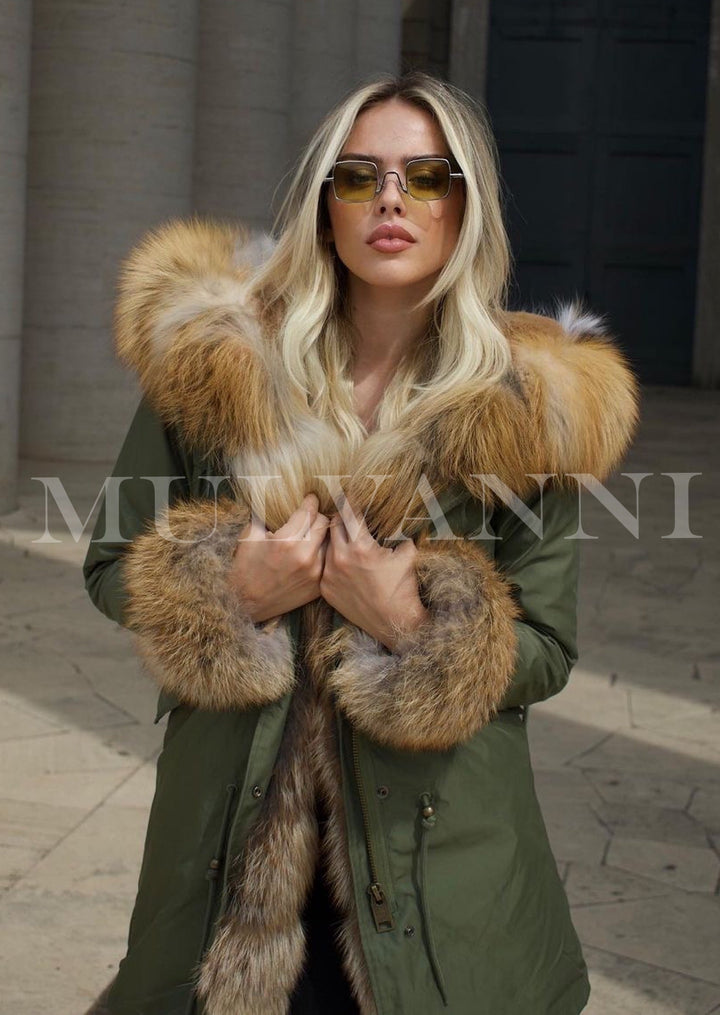 A woman dressed in a green parka with a striking red fox fur lining. The fur accents provide a touch of luxury, making the coat both functional and fashionable for winter outings.
