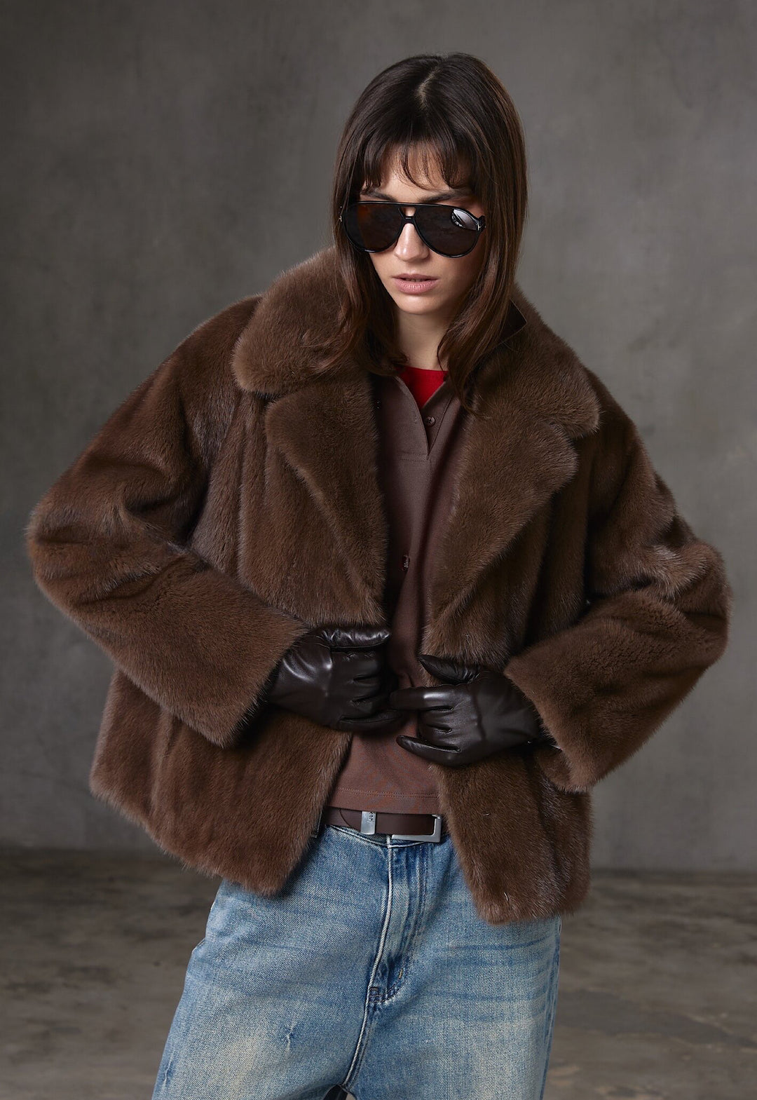 A woman models a luxurious short brown mink fur coat featuring natural sheen and classic elegance, accessorized with stylish sunglasses.