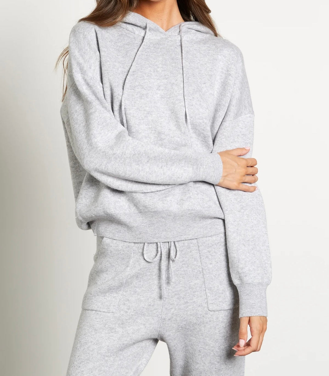 A woman wearing a comfortable grey cashmere wool set, including a sweater with a luxurious fox fur trim and matching trousers. This set blends casual luxury with warmth, ideal for a relaxed yet fashionable winter outfit.