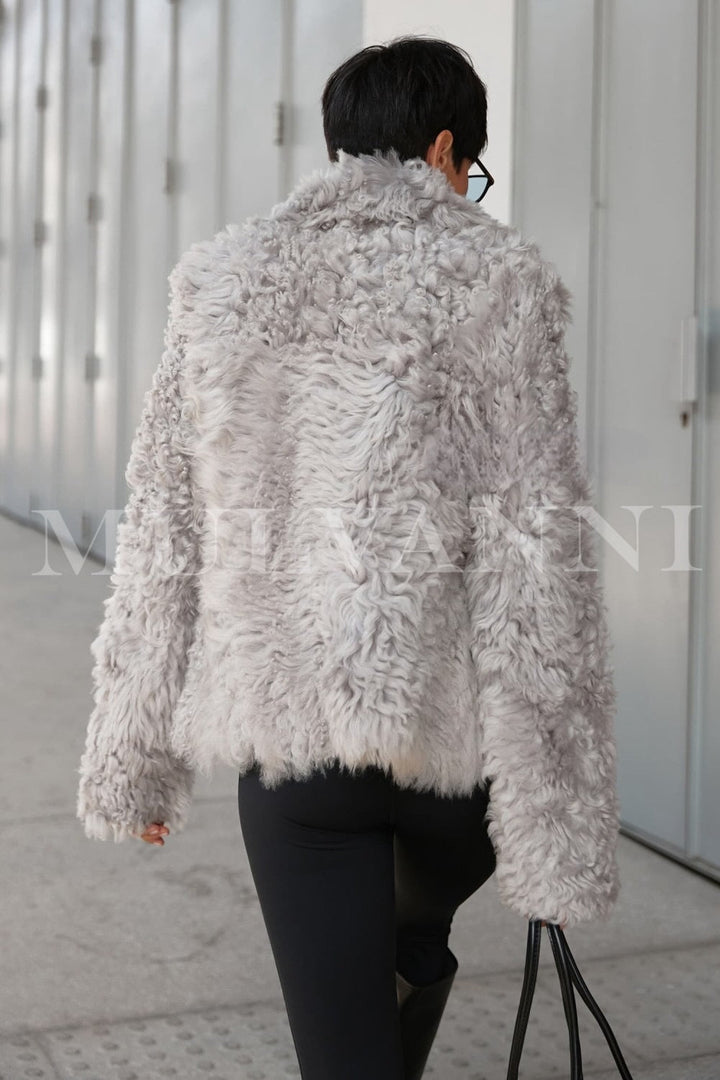 Modern winter outfit showcasing a woman in a premium grey shearling coat, styled with a black leather bag to elevate the understated, classic ensemble.