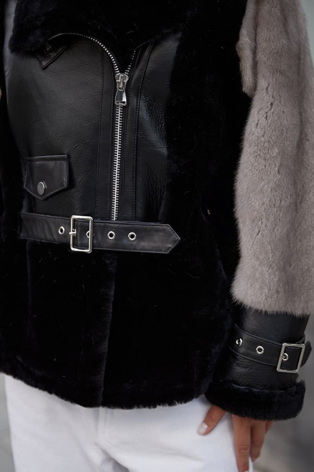 Close up of a leather jacket with grey mink sleeves. 