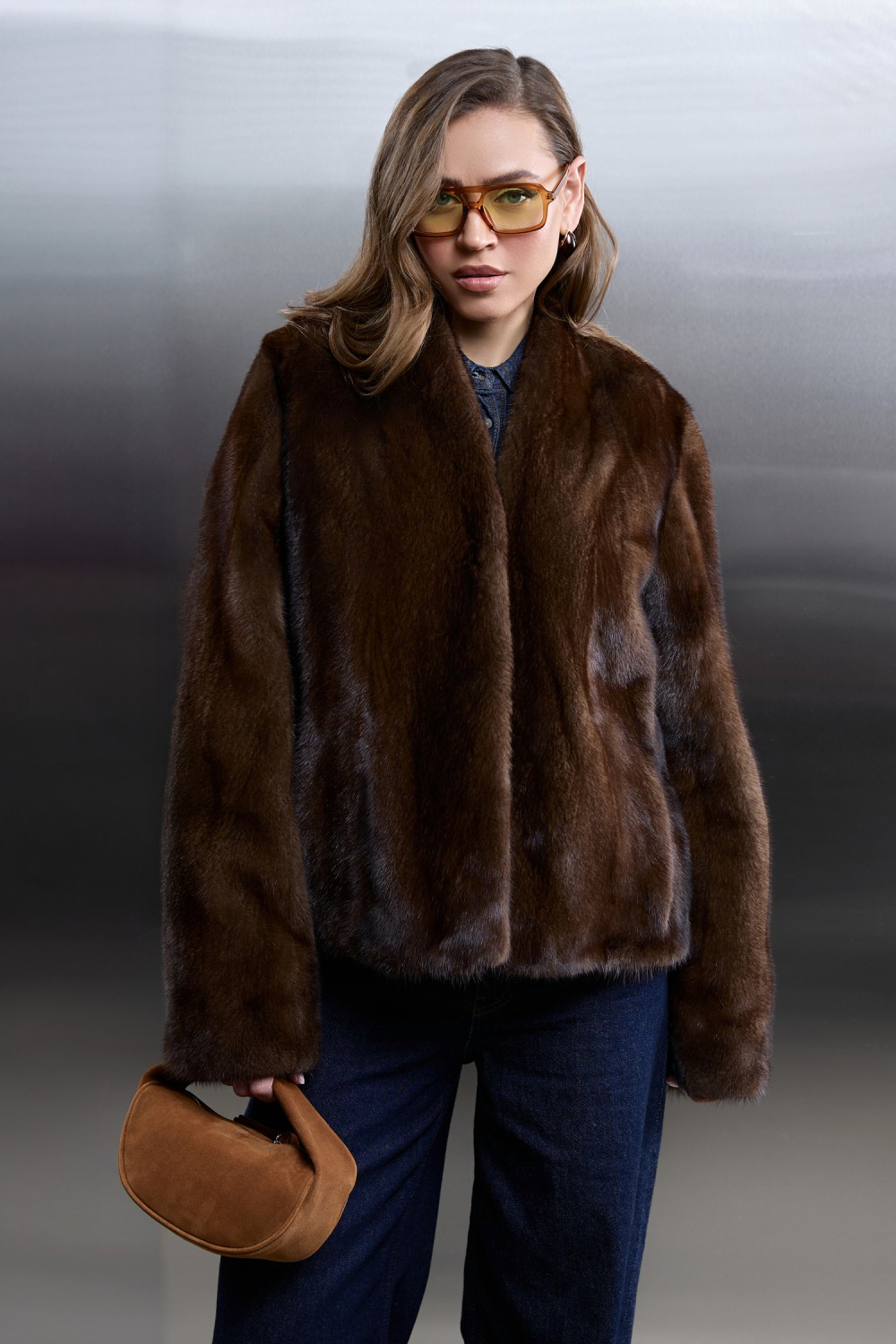 Model in a stylish brown mink fur coat with a short design, paired with denim and vintage-inspired sunglasses.