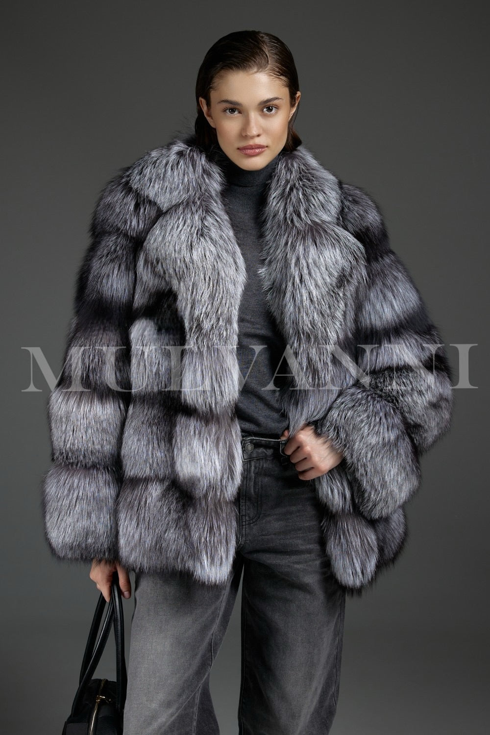 Woman wears a voluminous Silver Fox Fur Coat paired with a sleek black leather handbag, creating a bold and fashionable winter statement.