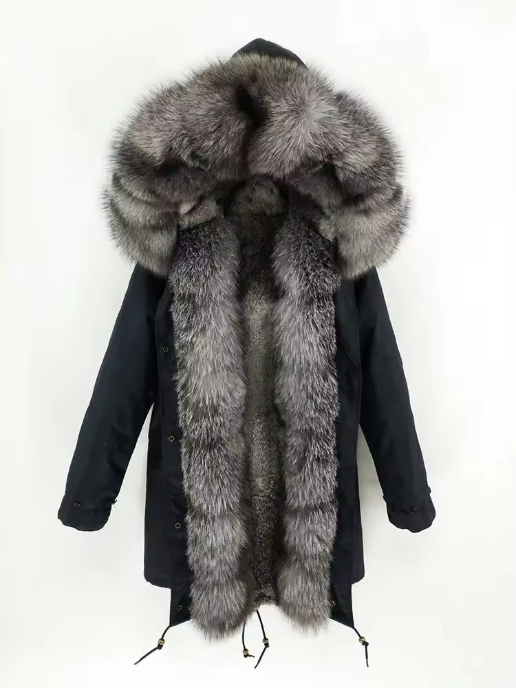 Full‑body view of a weatherproof black down parka with fox fur trim, raglan sleeves, waist drawstring, and dual fastenings—zip plus button tab—for enhanced cold protection.