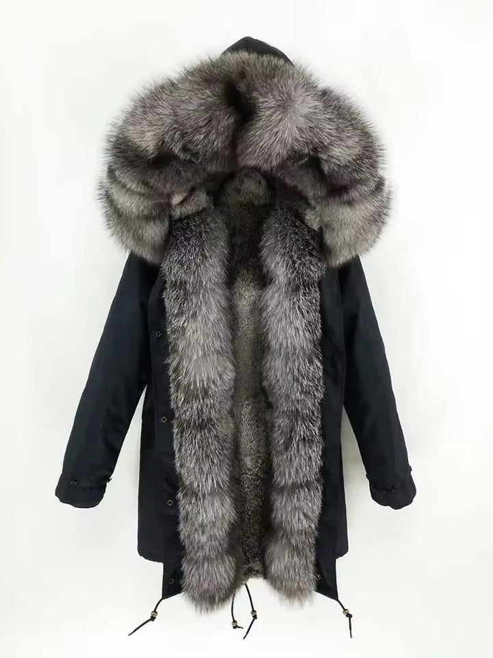 Full‑body view of a weatherproof black down parka with fox fur trim, raglan sleeves, waist drawstring, and dual fastenings—zip plus button tab—for enhanced cold protection.