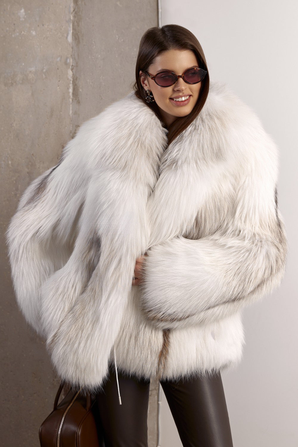 A woman models a sumptuous white fox fur coat with a relaxed, oversized fit, draping elegantly over the body for a glamorous and warm statement piece.