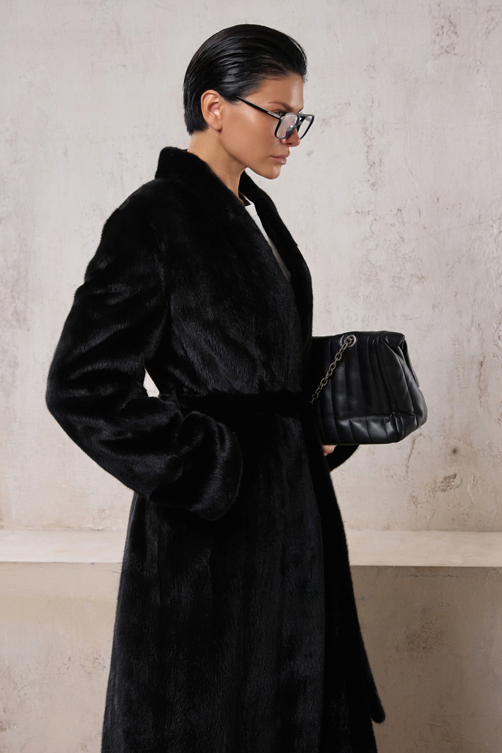 Elegant woman in a long black mink coat, showcasing luxury and versatility for formal or sporty outfits.
