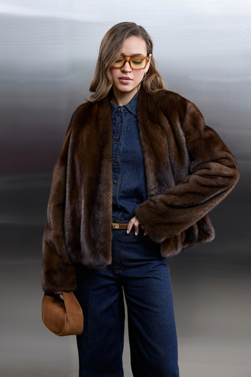 Stylish woman in a brown mink fur coat, combining elegance with casual denim outfit for a fashionable look.