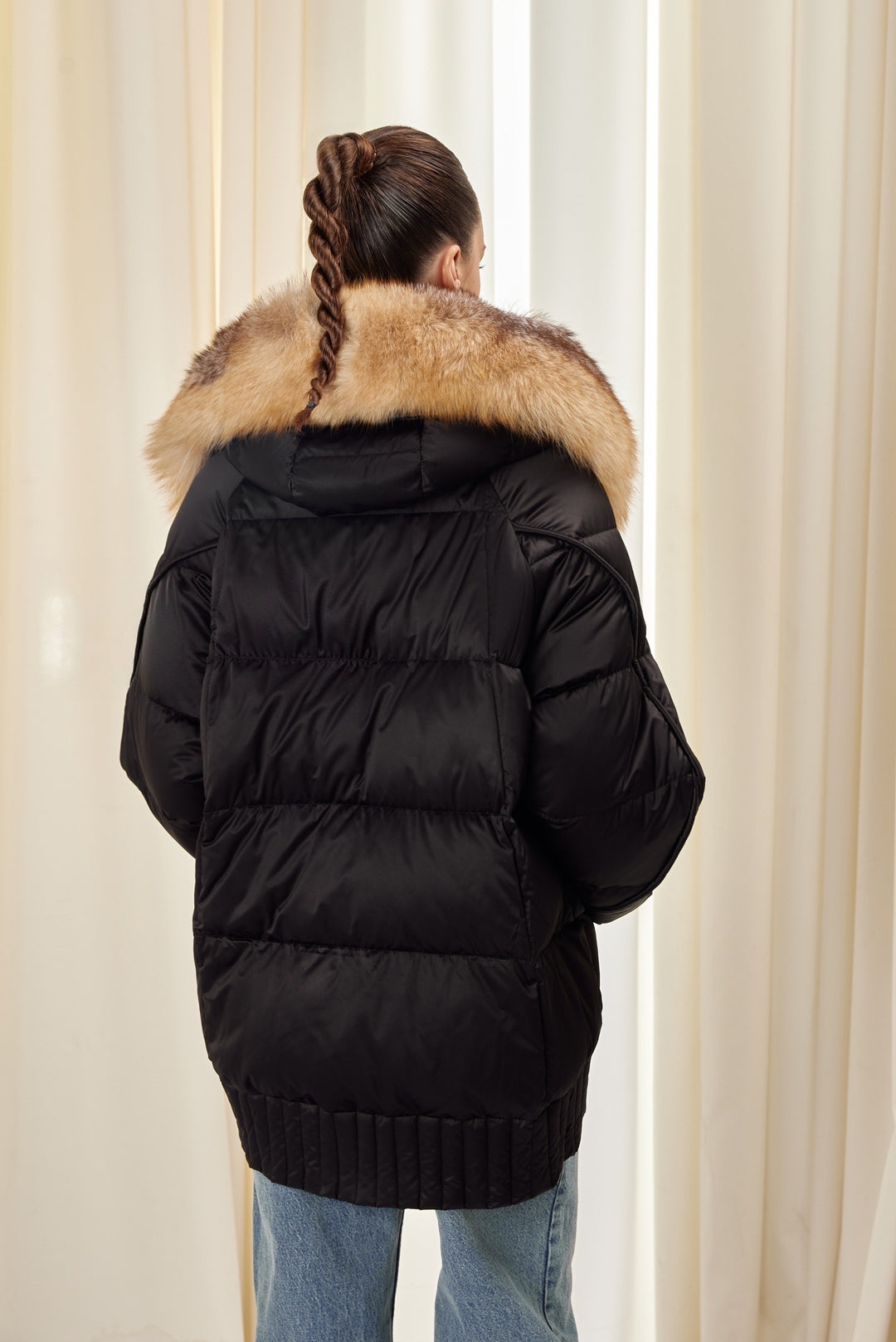 A woman dressed in a warm black down jacket accented with a luxurious fox fur hood, combining practicality with elevated winter style.
