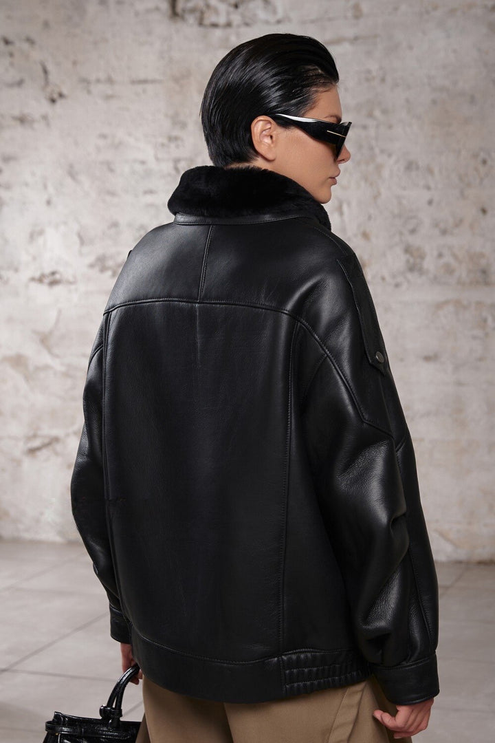 A woman dressed in a high-neck, oversized sheepskin jacket lined with soft shearling, showcasing a refined yet casual look ideal for cool weather layering.