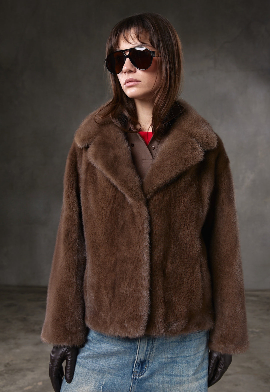 A woman wearing a short brown mink fur coat with a rich, velvety texture, paired with trendy sunglasses for a modern yet sophisticated look.