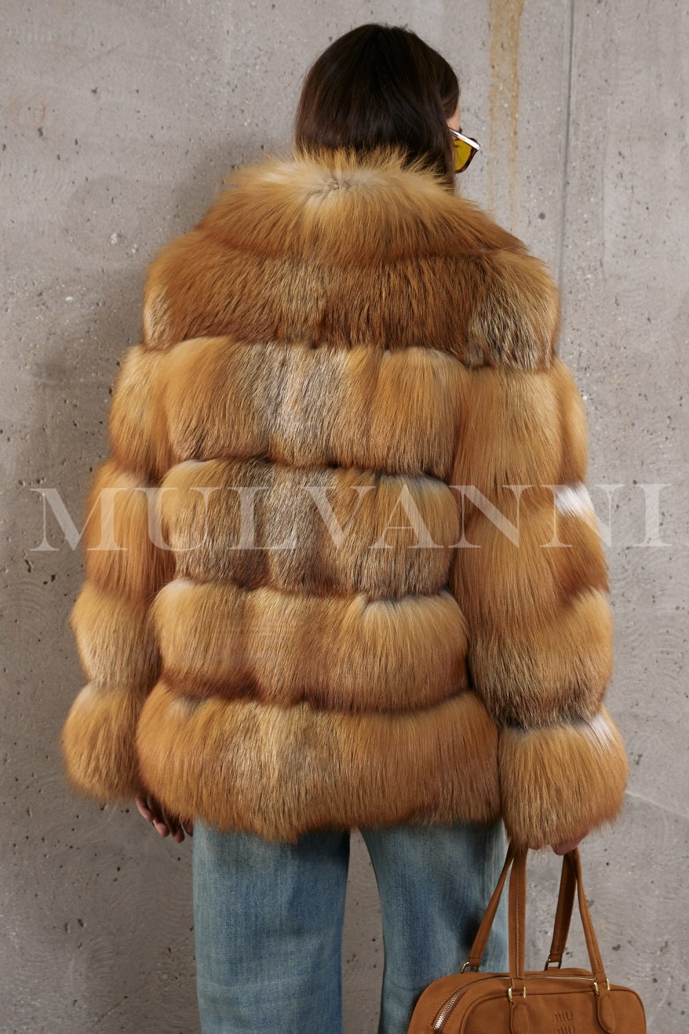 Red fox fur coat styled with denim for a modern take on timeless luxury, worn by a woman with graceful poise.