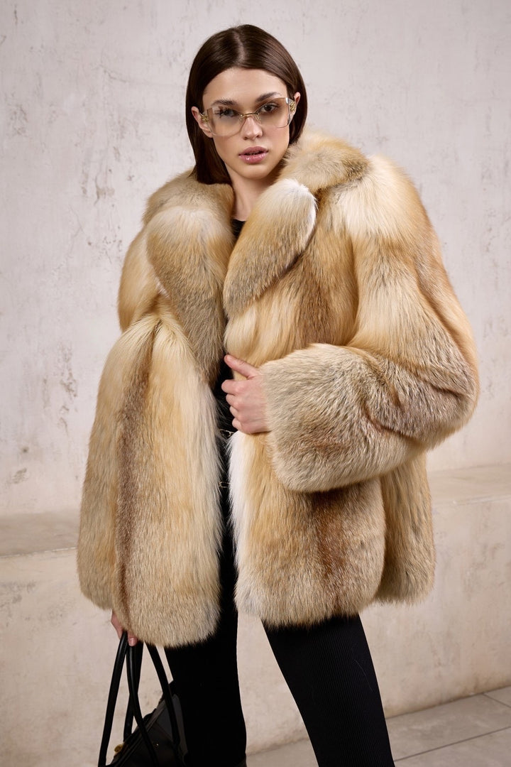 A woman dressed in a luxurious full pelt gold fox fur coat, perfect for Arctic temperatures, styled with sleek sunglasses for a striking, high-fashion winter look.