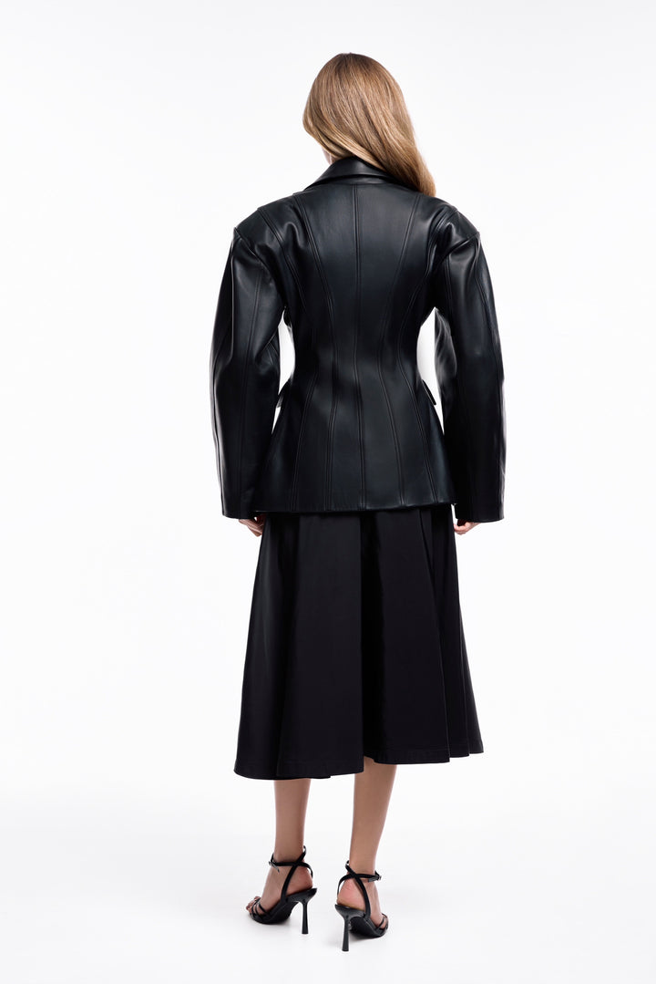 A woman models a sleek black leather blazer jacket, crafted from supple leather and designed to flatter the figure, offering a modern take on classic sophistication.