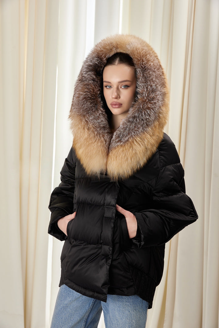 A woman wearing a black down jacket with a voluminous fox fur-trimmed hood, combining warmth and stylish winter protection.
